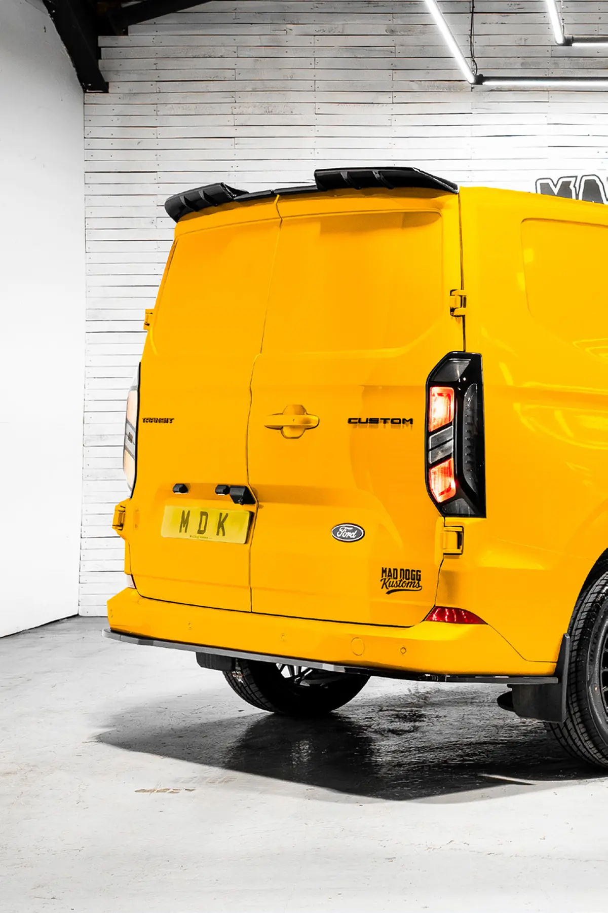 Rear view of a yellow Ford Transit Custom with spoiler
